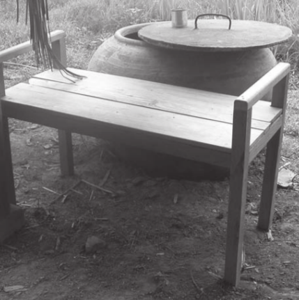 Un banc de bain en bois devant une jarre d'eau pour se laver