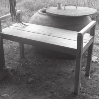 Un banco de madera para bañarse, frente a un recipiente de agua para lavarse